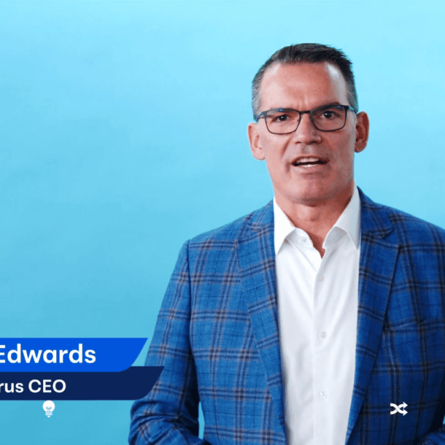 A man in a blue plaid suit and glasses speaks in front of a blue background. The text on the left reads, "Adam Edwards, Telarus CEO." The Telarus logo graces the top left corner, symbolizing innovation. His discussion highlights the dynamic future of Telarus Capital.